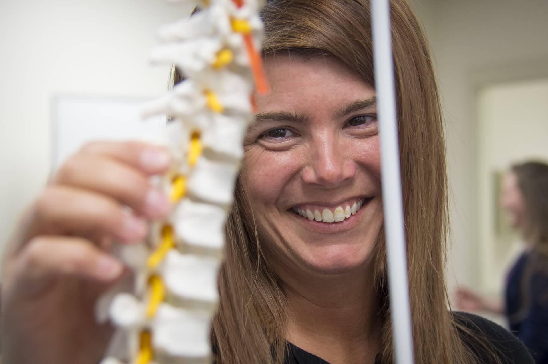 A female student holding up a replica spine